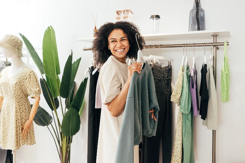 Laughing woman customer choosing sweatshirt at a store
