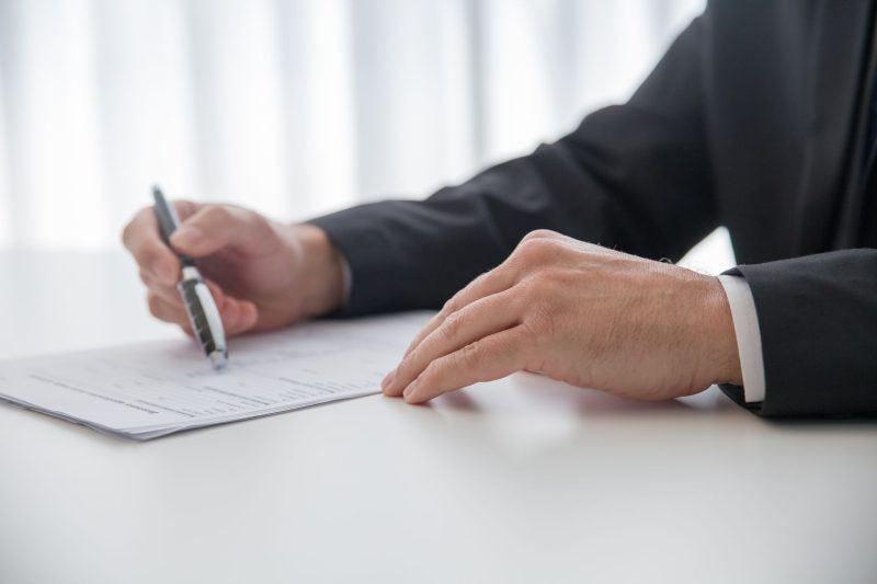 Businessman signing important documents at office desk 1785258602